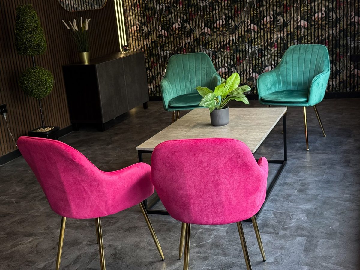 The waiting area at Oksana Kón Studio, with magenta velvet chairs and a planted wall.